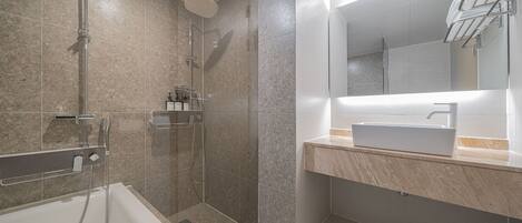 Un baño moderno con ducha de vidrio, bañera independiente y tocador con lavamanos.