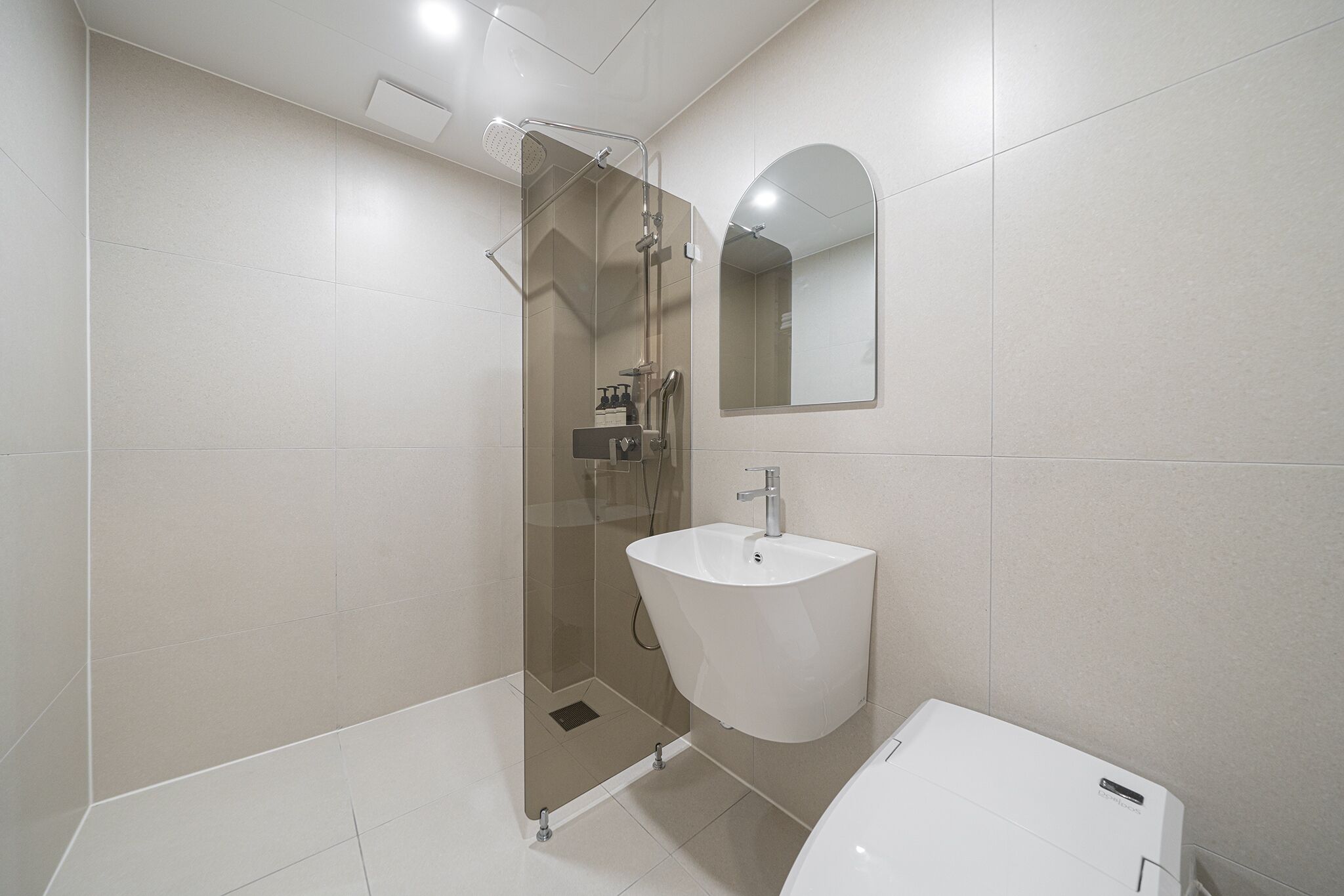 A modern bathroom with a glass-enclosed shower, a white sink, and a mirror above it.