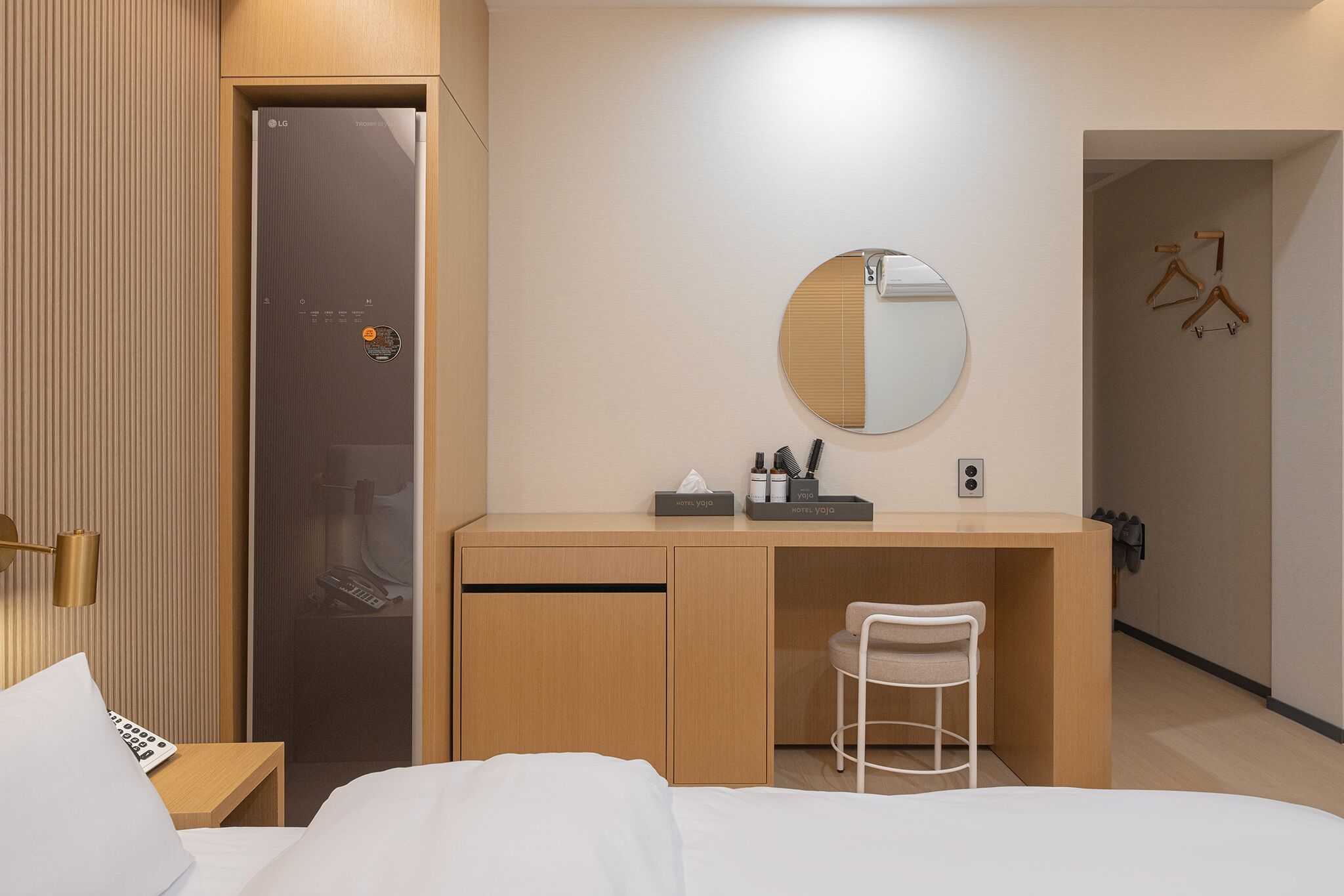 Ein Hotelzimmer mit einem Bett, einem Schreibtisch mit Spiegel, einem Sessel und einem Kleiderschrank.