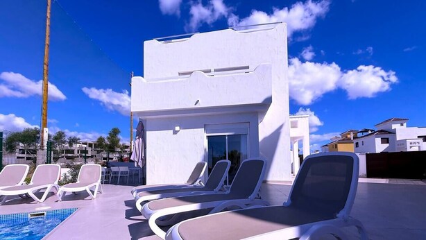 A poolside area with sun loungers, a small building, and a clear blue sky. - Villa Modern Princess (Golf Del Sur)