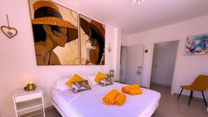 A hotel room with a large bed, white bedding, a nightstand with a lamp, and a painting on the wall. - Villa Modern Princess (Golf Del Sur)