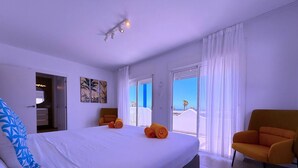 A bedroom with a large bed, a chair, and a view of the outdoors. - Villa  Red Princess - Private Heated Pool (Golf Del Sur)