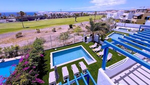 A pool area with lounge chairs and a view of the ocean. - Villa  Red Princess - Private Heated Pool (Golf Del Sur)