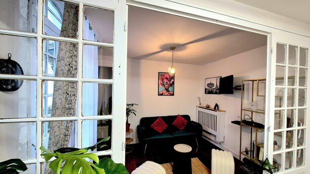 A modern living room with a black sofa, a coffee table, and a large plant. - House with fenced exterior and garage 2 steps from the spa. 2 adults/1 child  (Salies-de-Béarn)