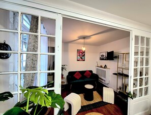 Een moderne woonkamer met een zwarte bank, een bijzettafeltje en een grote plant.