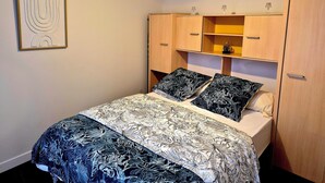 A bedroom with a bed, a headboard with shelves, a hanging light fixture, and a framed artwork on the wall. - House with fenced exterior and garage 2 steps from the spa. 2 adults/1 child  (Salies-de-Béarn)