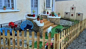 A courtyard with a wooden fence, potted plants, a blue chair, and a small white dog. - House with fenced exterior and garage 2 steps from the spa. 2 adults/1 child  (Salies-de-Béarn)