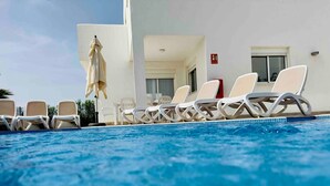 En pool med liggestole og et overdækket område.