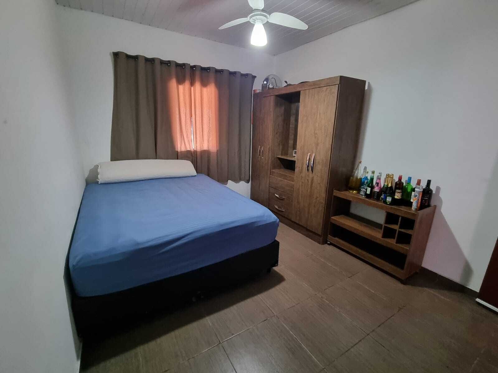 A bedroom with a bed, a wardrobe, and a shelf with bottles.