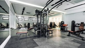 A modern gym with various exercise machines, benches, and mirrors. - Status Apartments 100 (Becici)