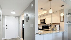 Cocina moderna con armarios blancos, encimera de granito e iluminación colgante.