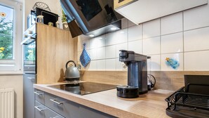Eine moderne Küche mit Einbauherd, Kaffeemaschine und Wasserkocher auf der Arbeitsplatte.