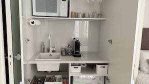 Un angolo cottura compatto dotato di forno a microonde, macchina da caffè e lavatrice.