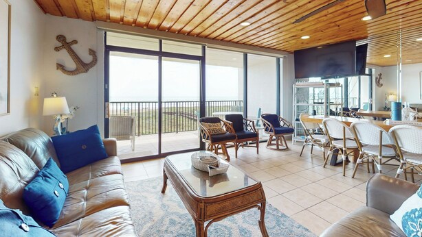 Un salón comedor amplio con techo de madera, un ventanal grande y un balcón.
