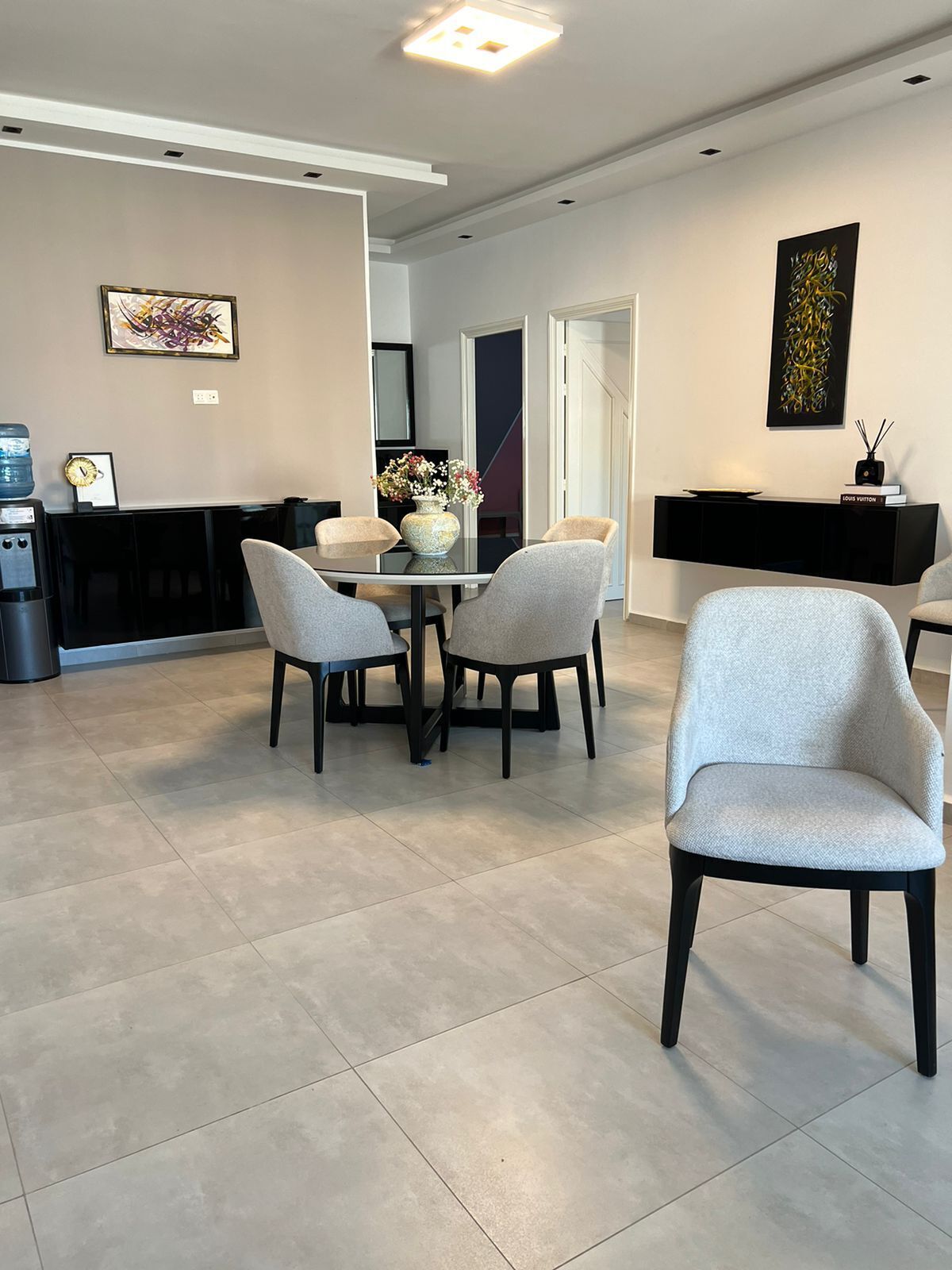 Un espace repas moderne avec une table en verre, quatre chaises et un vase rempli de fleurs.