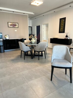 A modern dining area with a glass table, four chairs, and a vase with flowers.