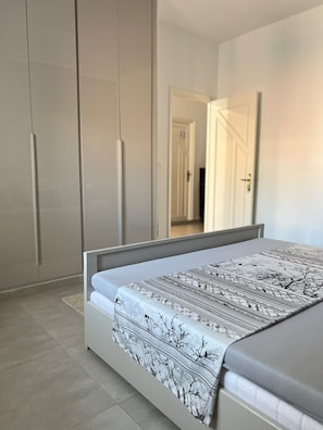 Un dormitorio con cama, armario y puerta que da a otra habitación.