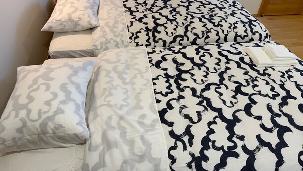 Ein Bett mit gemusterten Betttextilien und einem gefalteten Handtuch.
