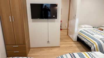 Ett hotellrum med två sängar, en TV som är monterad på väggen, ett träskåp och en brandsläckare i hallen.