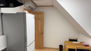 Eine kleine Küche mit Kühlschrank, Herd und einem Holzespeisetisch.