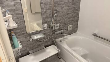A modern bathroom with a bathtub, a shower, a vanity with a mirror, and a towel rack.