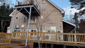 A two-story wooden house with a balcony and a deck.