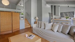 Un salon moderne avec un canapé, une table basse et un escalier menant à un niveau supérieur.