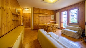 A wooden interior with a dining table and chairs, a bed, and a window with a view. - Casa D`Amato - Roccaraso (Roccaraso)