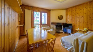 A wooden room with a dining table, chairs, a bed, a TV, and a fireplace. - Casa D`Amato - Roccaraso (Roccaraso)