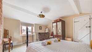 Ein Schlafzimmer mit Bett, Kommode, Spiegel, Fenster und Tür.