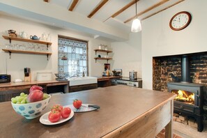A kitchen with a central island, a stone fireplace, and a window with decorative iron bars. - 4 Bed in Belper (oc-dcwod) (Paddocks)