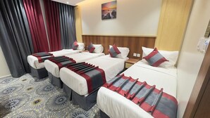 A hotel room with four beds, each with a red and grey striped bedspread, a wooden headboard, and a large window with red curtains. - Masar Almisk Hotel (Makkah)