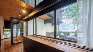Een modern interieur met een houten plafond, grote ramen en een bank langs het raam.