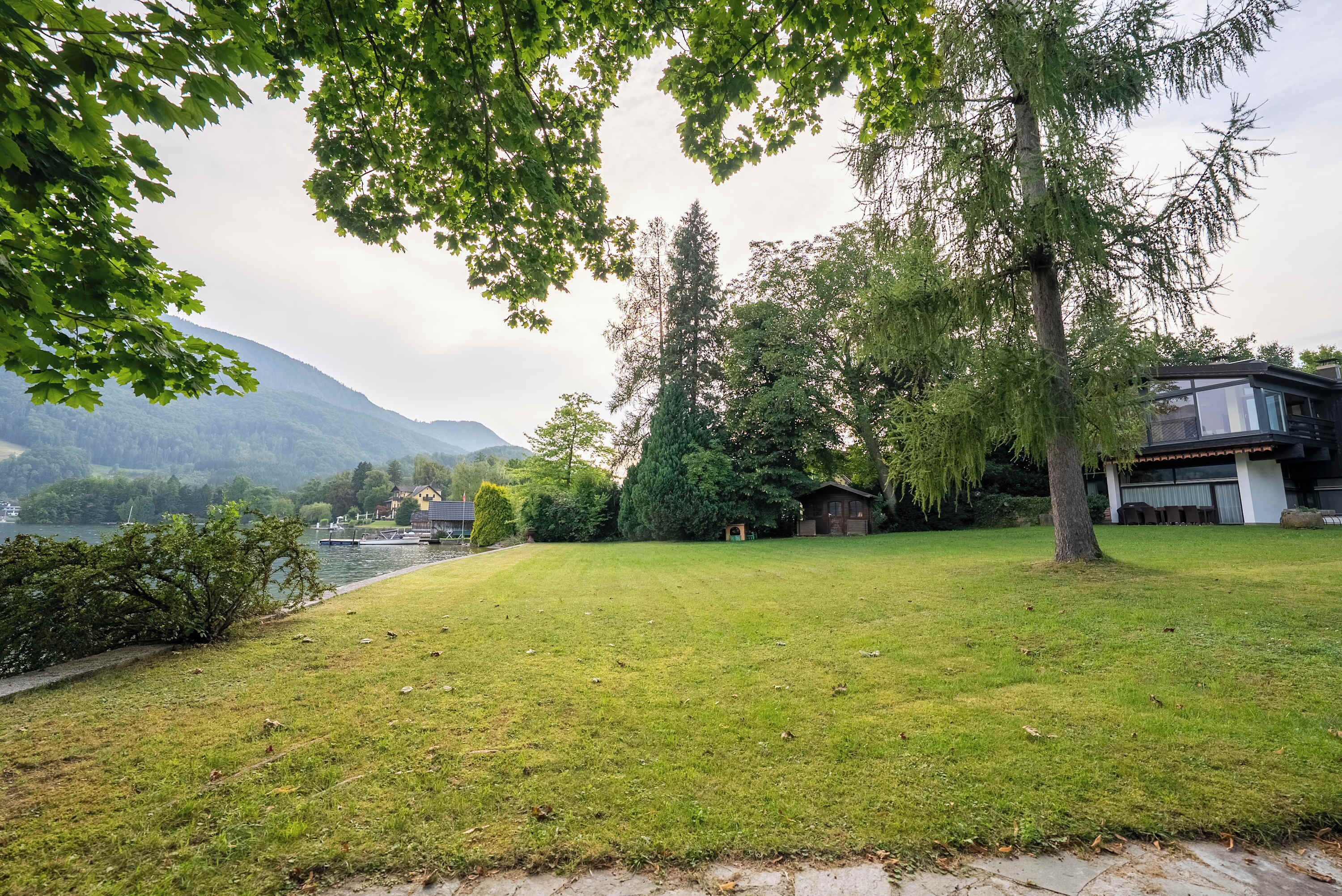 Une cour verdoyante avec une maison et un lac en arrière-plan.