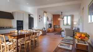 A spacious living area with a wooden dining table, comfortable seating, a fireplace, and a view of the outdoors. - Beautiful brand new villa with pool - DiCasaInSicilia (Menfi)