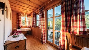 A wooden cabin interior with a dining table, chairs, and a window with plaid curtains. - Apartment Narzisse | Lakefront | Kitchen | Parking (Gößl)