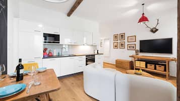 Una cucina moderna con mobili bianchi, un tavolo da pranzo in legno e una lampada a sospensione rossa.