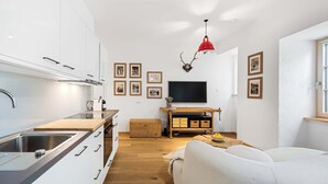 Une cuisine moderne avec des armoires blanches, un plan de travail en bois et un luminaire suspendu rouge.