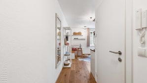 A narrow hallway with wooden flooring, white walls, and a door leading to a room with a white telephone and a light fixture. - Superior Studio | Kitchen | Parking | Central (Bad Aussee)