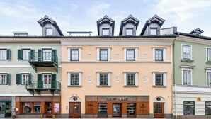 A row of multi-story buildings with balconies, storefronts, and a shop named 'buer optik'. - Superior Studio | Kitchen | Parking | Central (Bad Aussee)