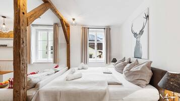 Une chambre avec un grand lit, une poutre en bois au plafond et une fenêtre avec des rideaux.