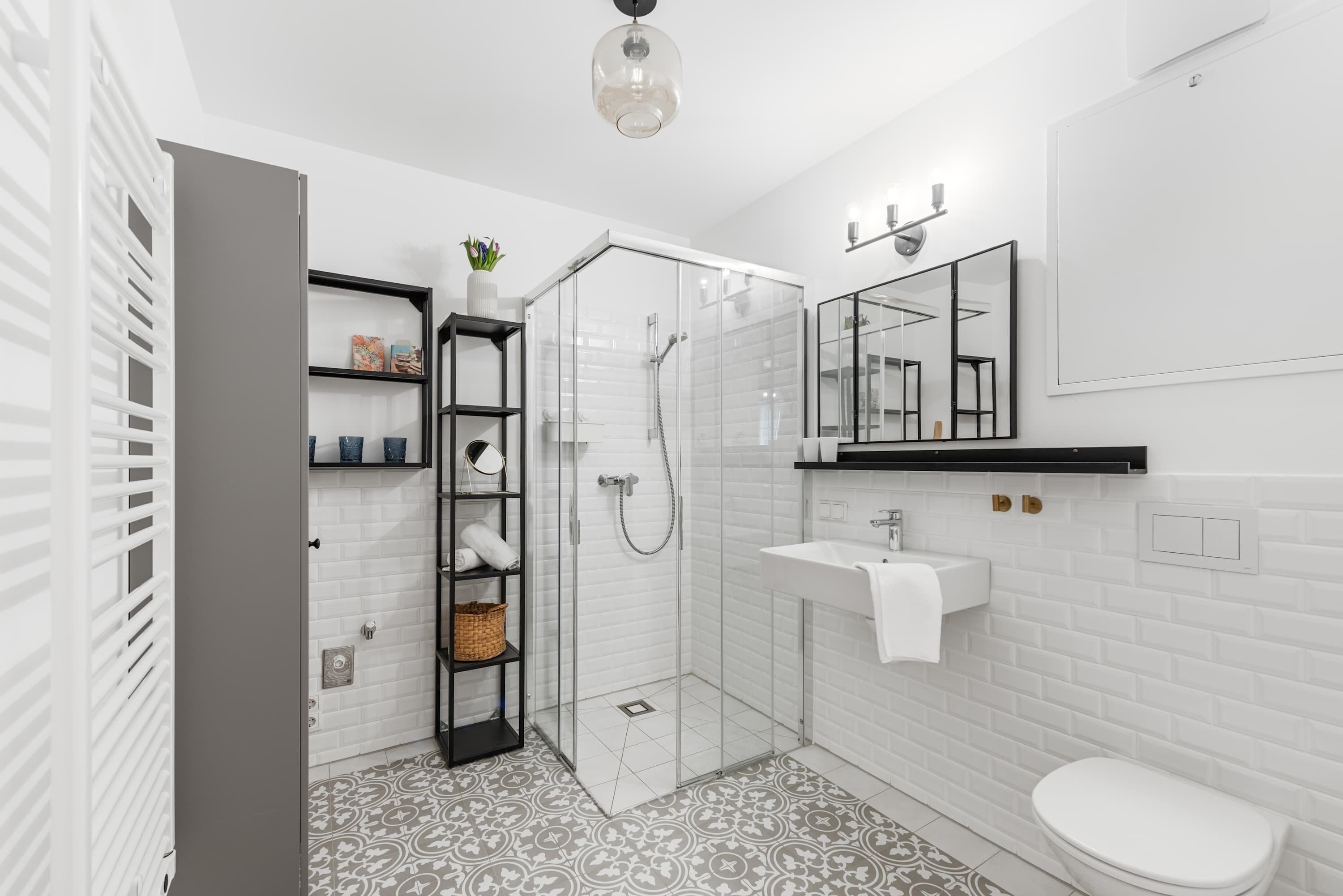 Un bagno moderno con box doccia in vetro, lavandino bianco e uno specchio grande.