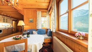 L’intérieur chaleureux d’un chalet comprend une table à manger, un canapé et une fenêtre donnant sur les montagnes.