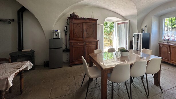 Eine Küche mit Esstisch, Stühlen, einem Kühlschrank, einem Herd und einem Schrank.