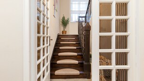 A staircase with wooden steps and a handrail, leading to a landing with a window and a potted plant. - Apartment 'Suite Seeblick' with Lake View, Private Garden and Wi-Fi (Holzappel)