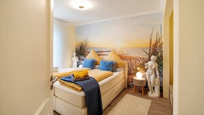 A bedroom with a bed, a nightstand, a wall mural, and a statue. - Apartment 'Suite Seeblick' with Lake View, Private Garden and Wi-Fi (Holzappel)