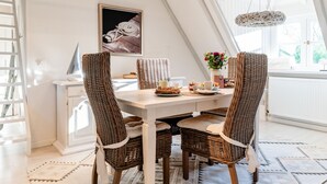 En matplats med ett vitt bord, flätade stolar och en inramad tavla på väggen.