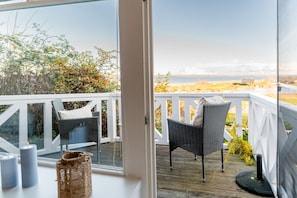 Un balcon avec des fauteuils en osier et vue sur la mer.