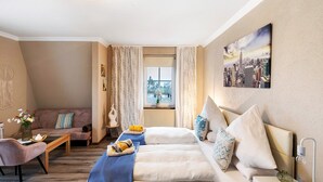 A cozy room with a sofa, a bed with pillows, a small table with a vase, and a window with curtains. - Holiday Home 'Pension Seeblick' with Lake View, Private Garden and Wi-Fi (Holzappel)