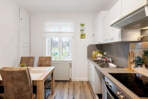 A compact kitchen with a dining table, chairs, a window, and a stove.
